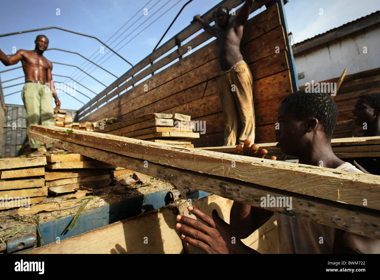 Men unload wooden boards from a truck at the timber market in Tema, Ghana on Tuesday May 20, 2008. Stock Photo