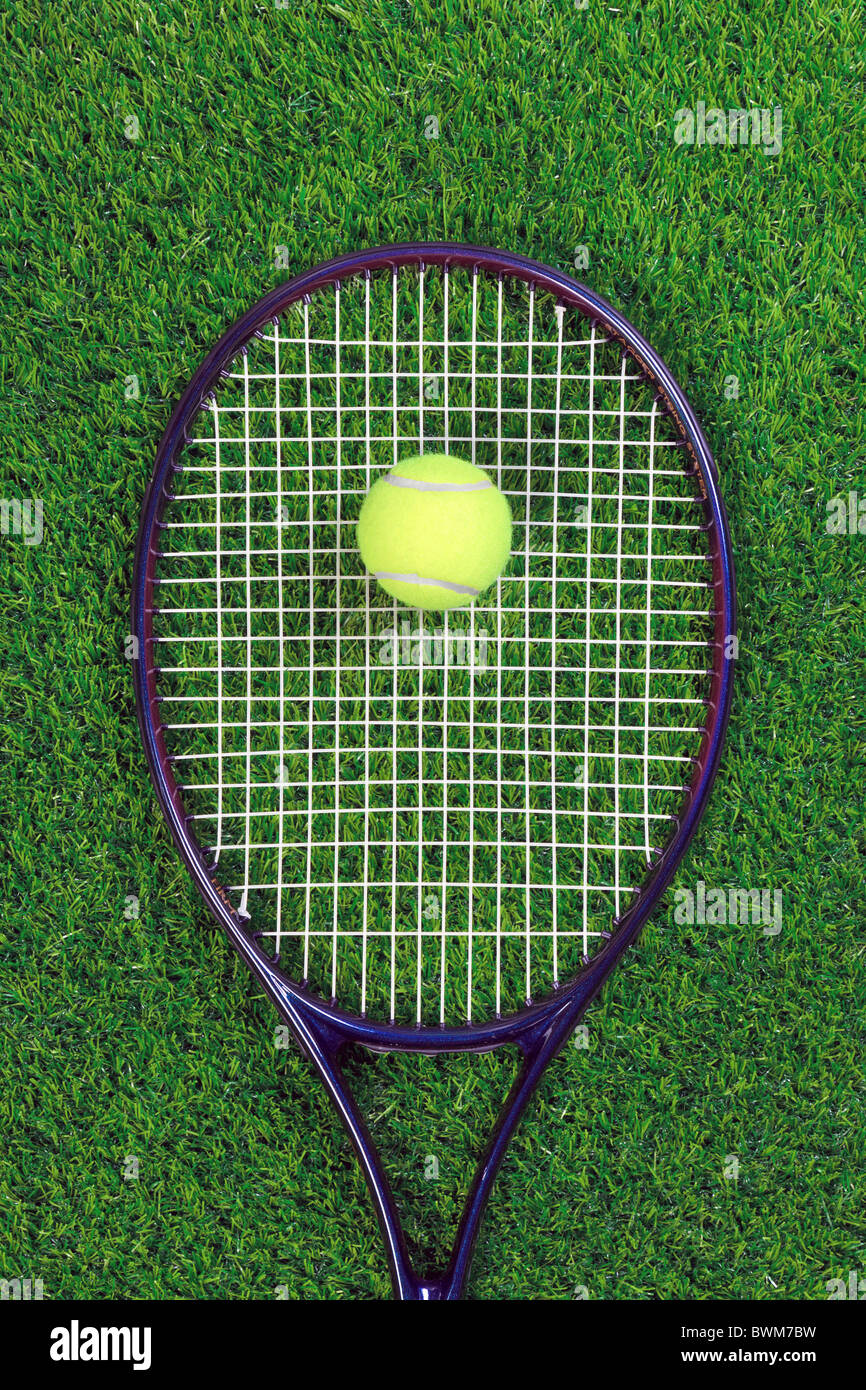 A tennis raquet or racket and yellow ball on grass. Stock Photo