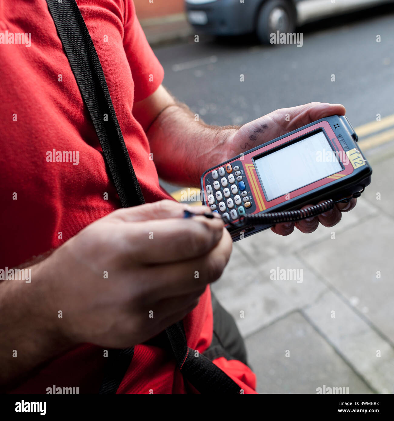 a Royal Mail postman using a hand-held digital device to record ...