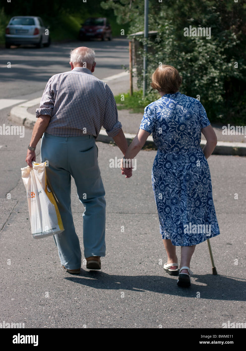 An elderly couple walk down the street holding hands in Prague, Czech Republic Stock Photo