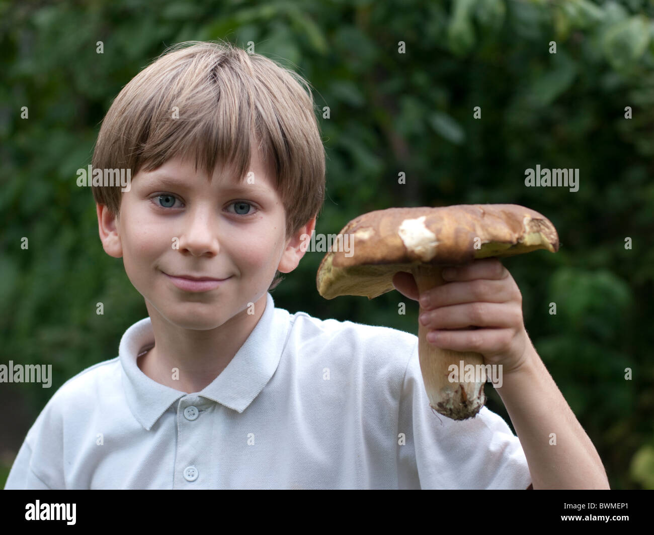 Ten year old boy holds up a boletus mushroom that he has foraged Stock Photo