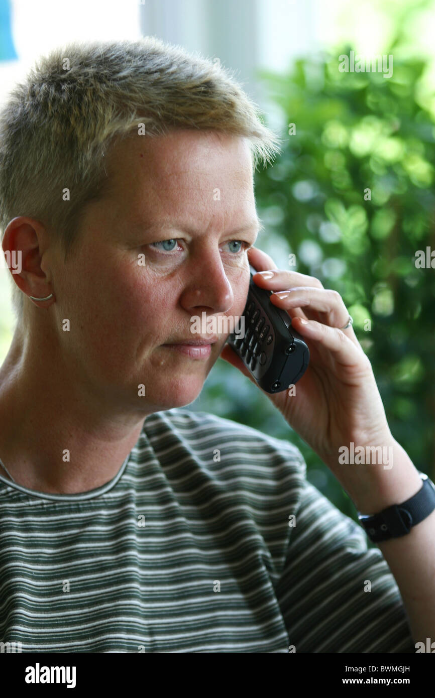 1990s: Serious adult woman listening to her cell phone at home, could be bad news call Stock Photo