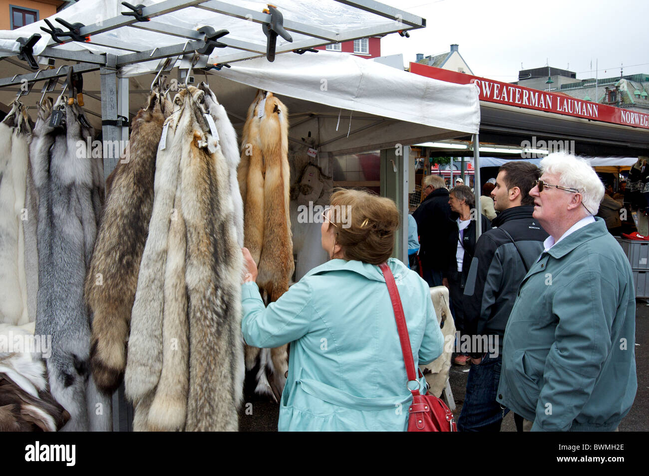 Tourists browse the wolf skin on sale in Bergen's outdoor market, Norway, Scandinavia Stock Photo