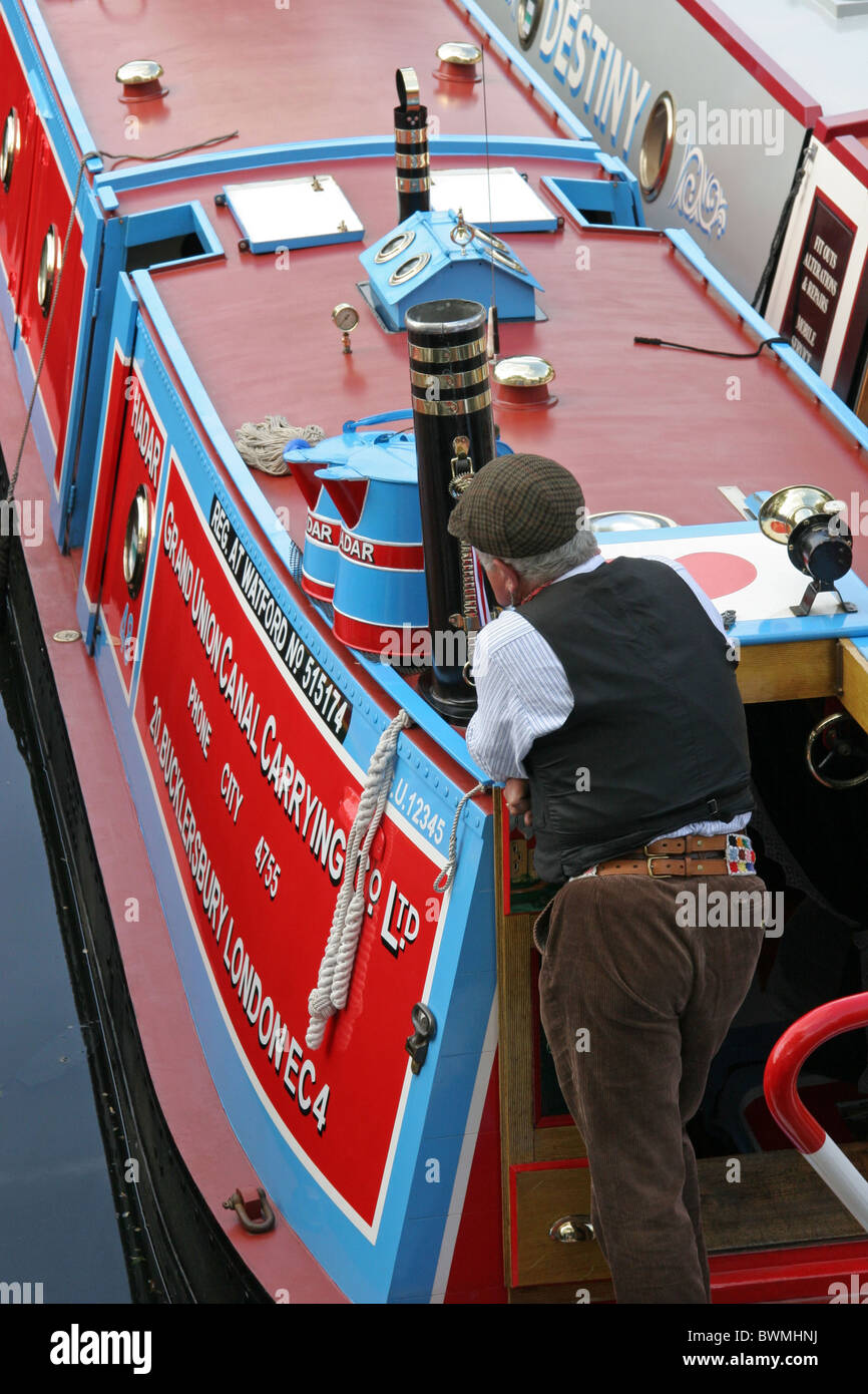 man in traditiona costume aboard Hadar, a norrow boat in the livery of the Grand Union Carring Co.Ltd. Stock Photo