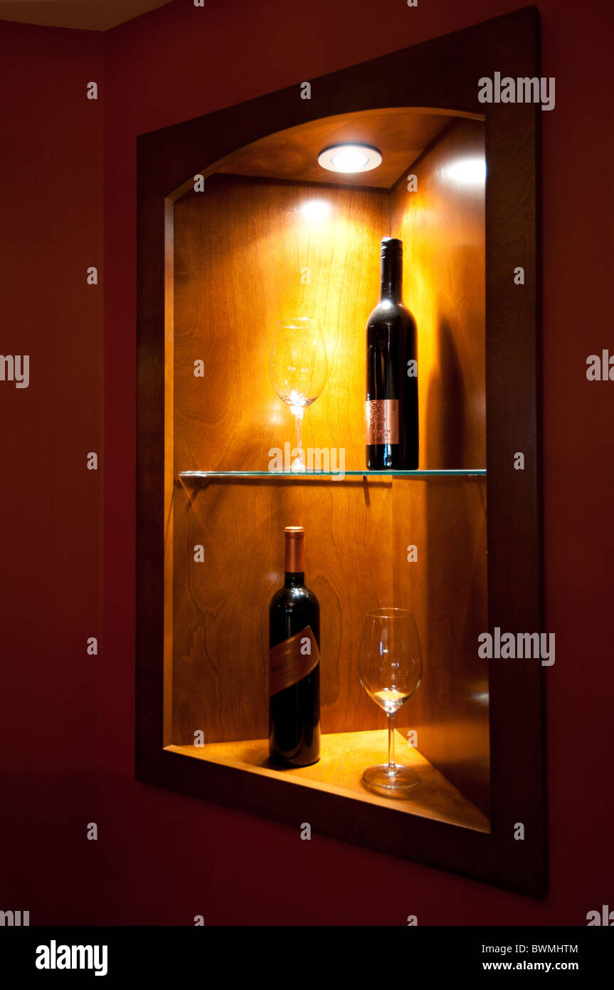 Wine bottles with accompanying glasses in a wall alcove in a luxury residential basement. Stock Photo