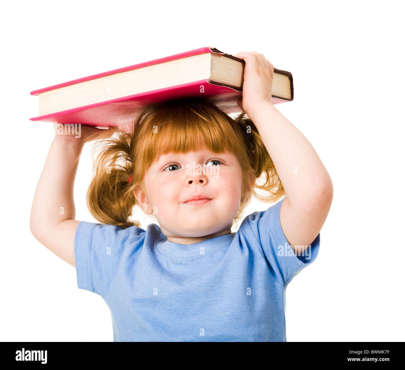 Portrait of young smiling child holding textbook over her head Stock ...