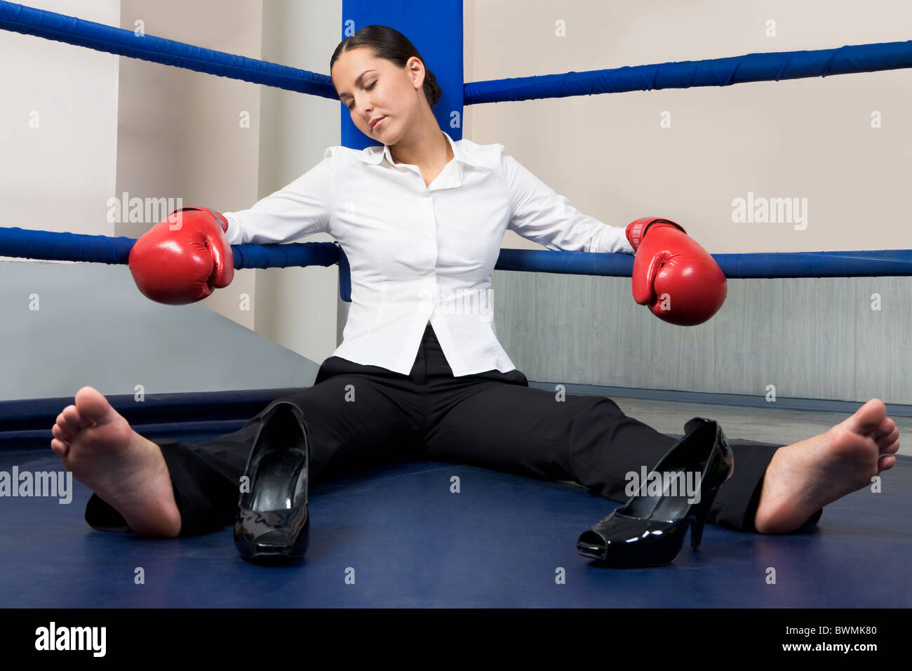 Portrait of tired businesswoman in boxing gloves sleeping on boxing