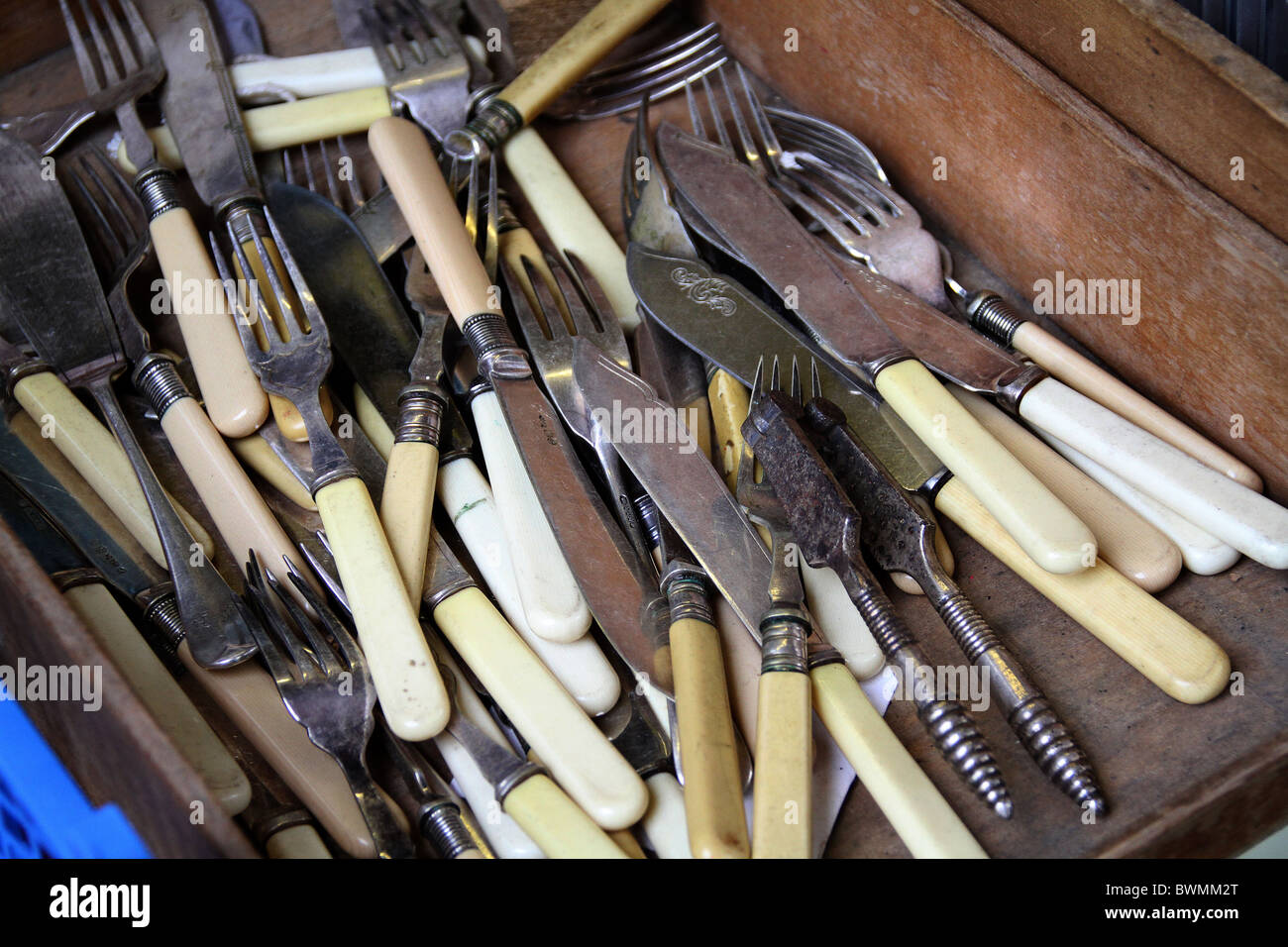 Old cutlery in a box for sale outside a junk shop. Stock Photo