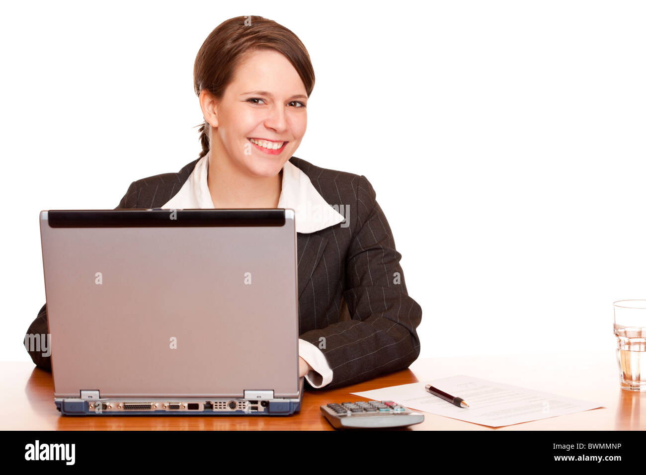 Young business woman sitting happy in office and works on computer. Isolated on white background. Stock Photo