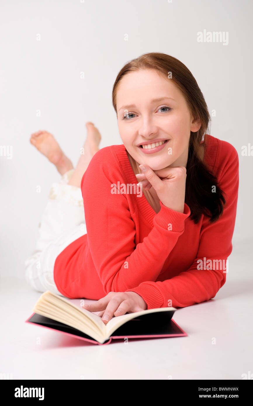 Young woman lying on the floor with book Stock Photo - Alamy
