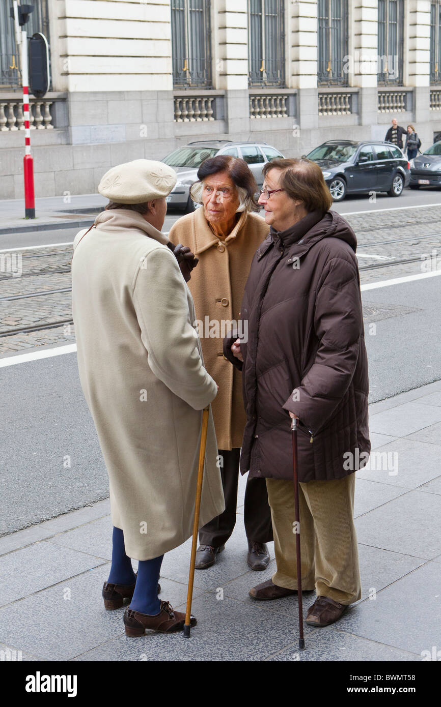 three old ladies 3 senior citizens elder elderly 60 70 80 90 years cane walking stick talk talking conversation gossip company w Stock Photo