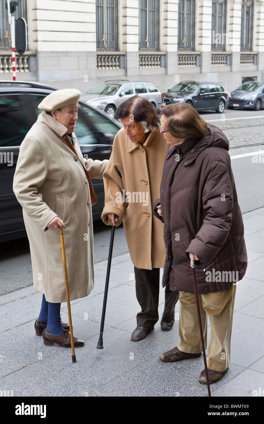 three old ladies 3 senior citizens elder elderly 60 70 80 90 years cane walking stick talk talking conversation gossip company w Stock Photo