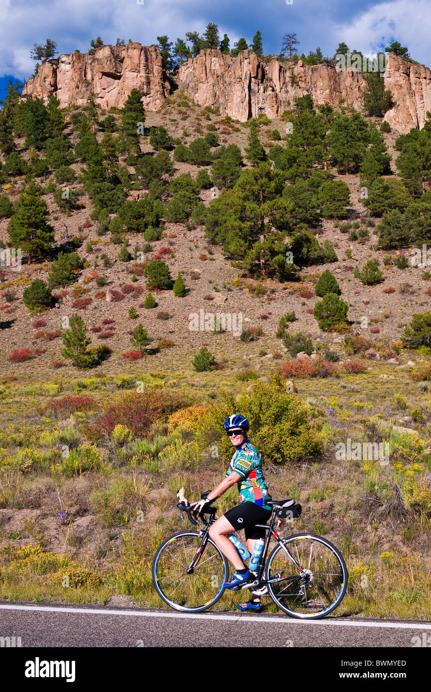 Cyclist passing the Rio Grande Palisades on Highway 149, Rio Grande National Forest, Colorado Stock Photo