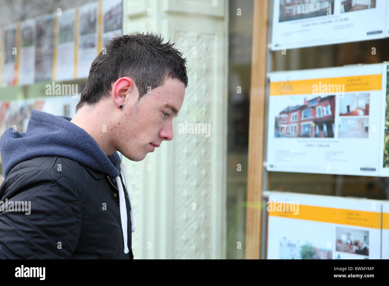 A first time buyer viewing houses in an estate agents window. Stock Photo