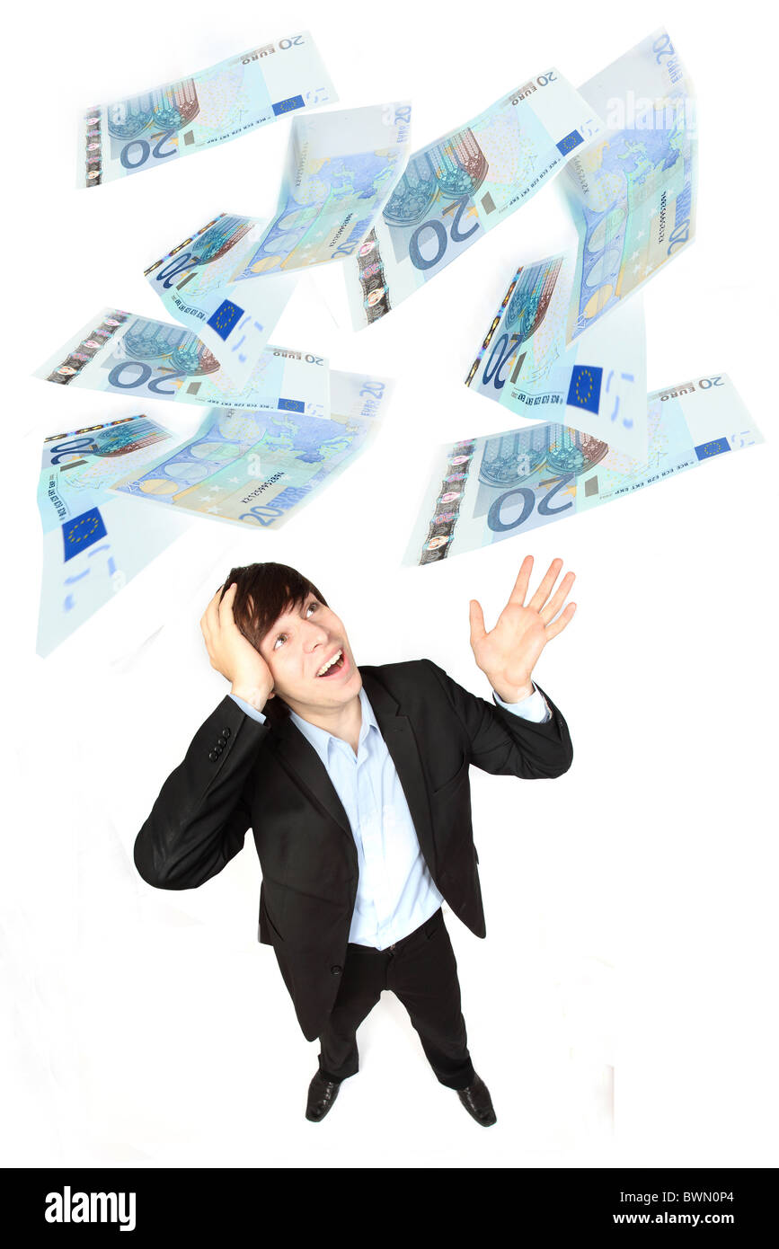 Young male wearing a suit, hand on his head amazed as Euros fall from above. Stock Photo