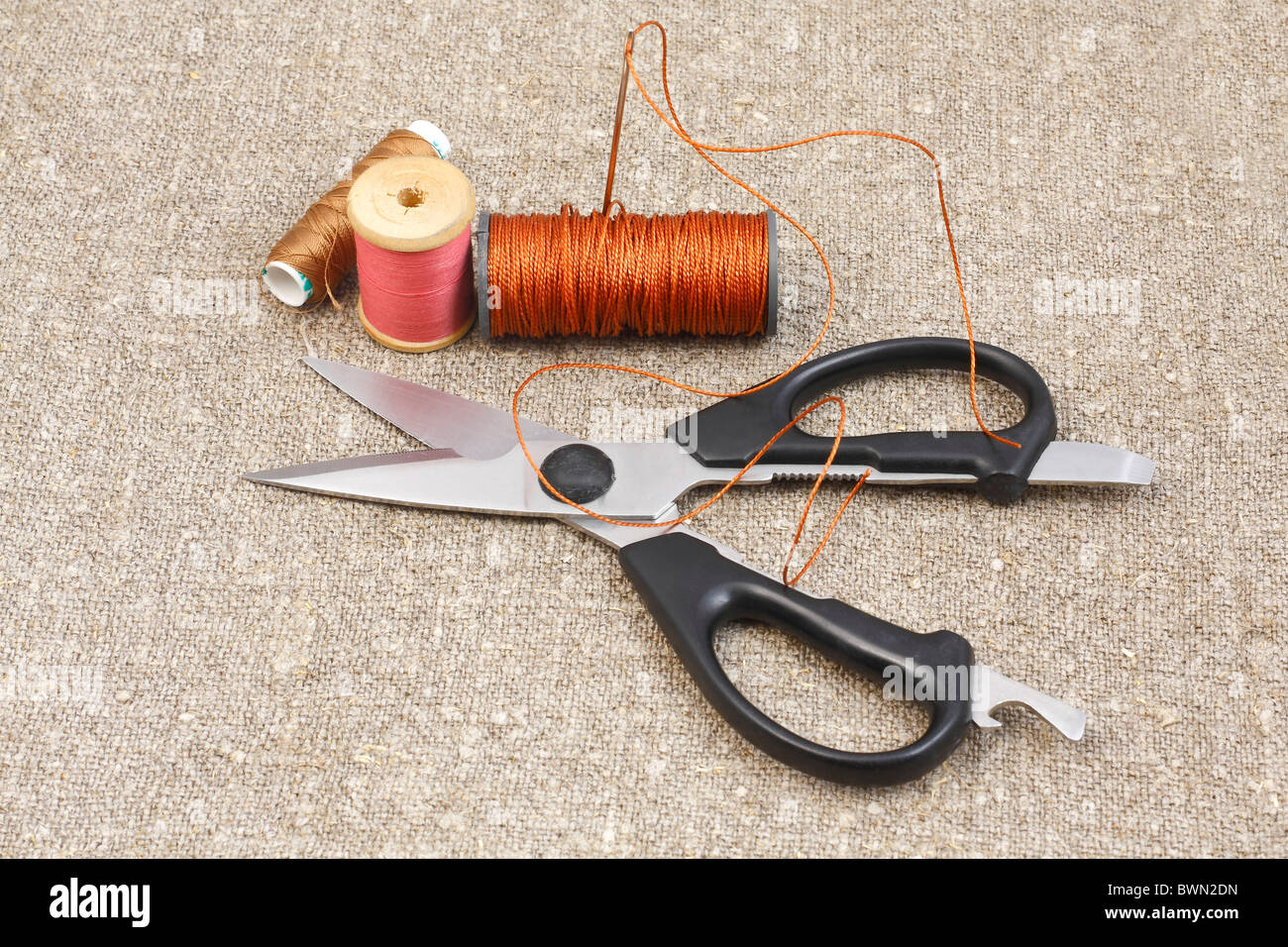 scissors, needle and thread on canvas of mats Stock Photo