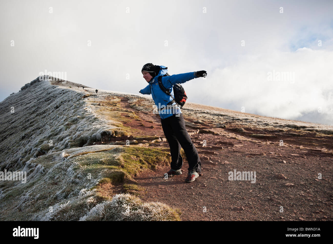 Female hiker leans into strong wind on side of Corn Du, Brecon Beacons national park, Wales Stock Photo