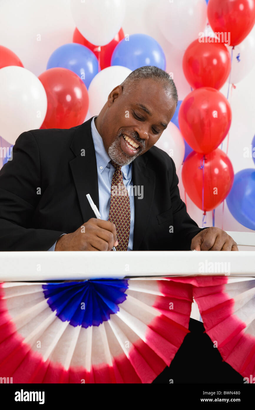USA, Illinois, Metamora, Smiling man writing at polling place table, balloons in background Stock Photo
