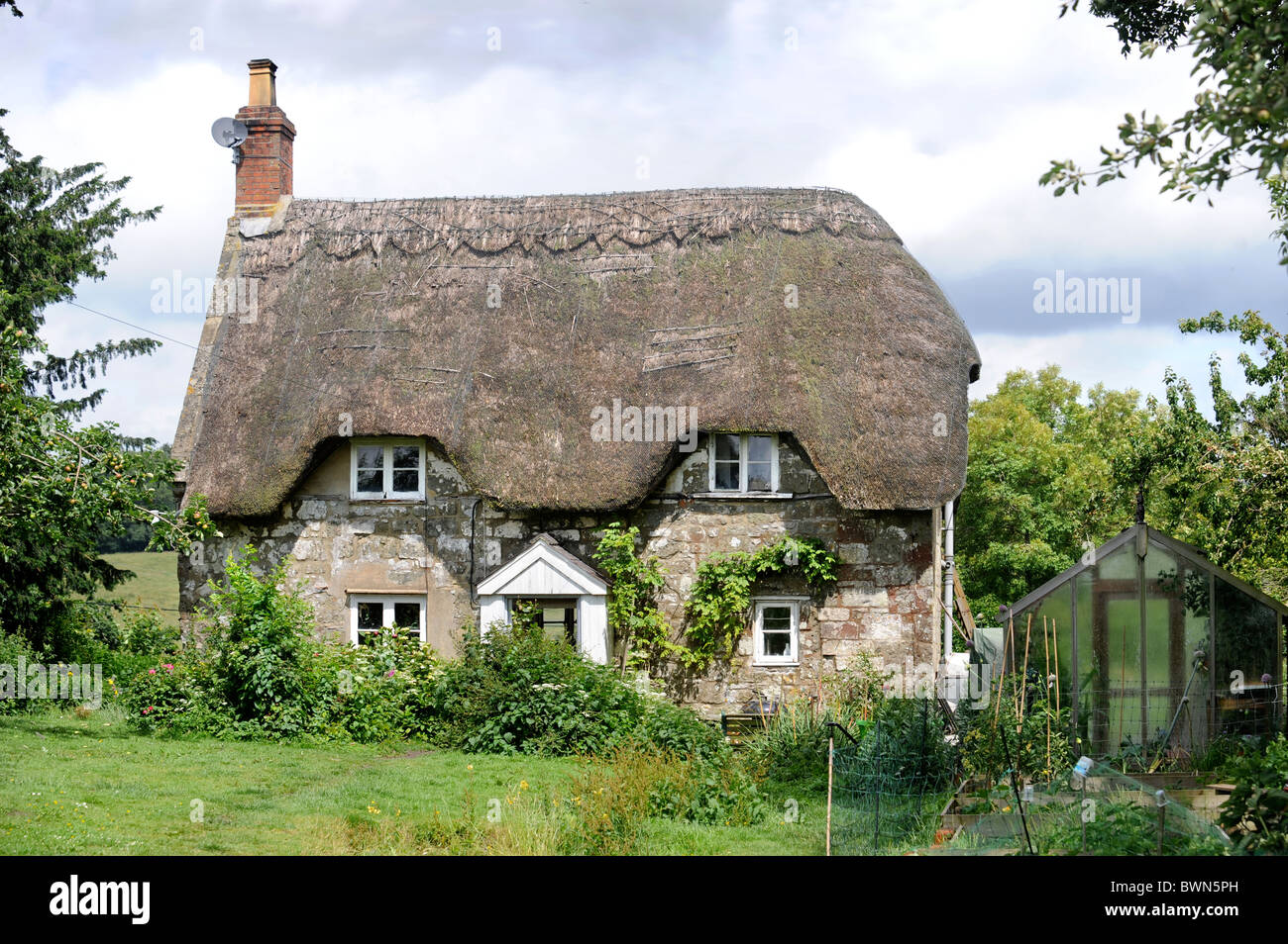 A thatched cottage with chickens in the garden Wiltshire, UK Stock Photo