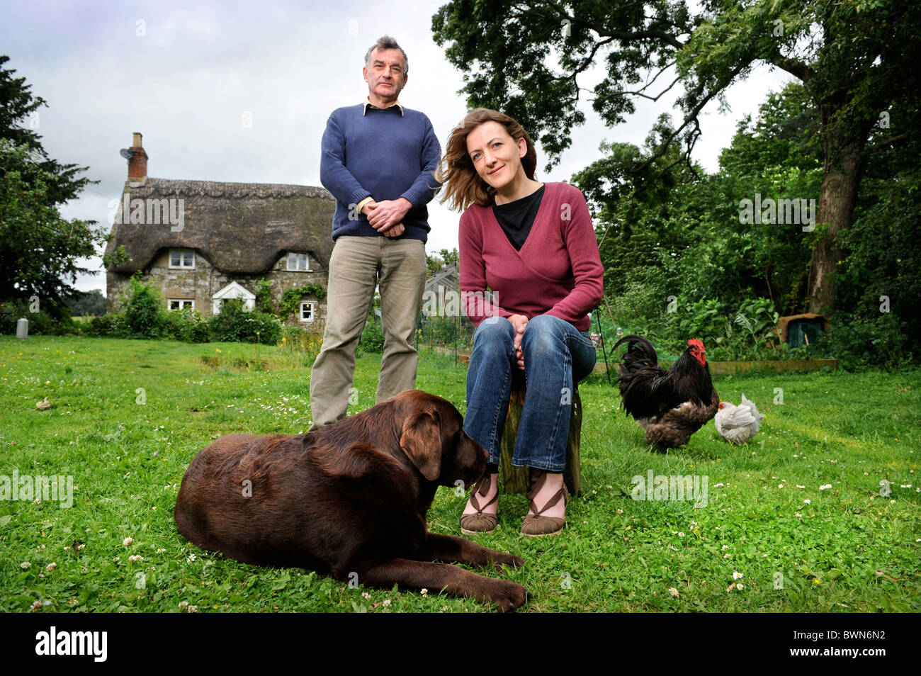 Owner of a thatched cottage with her pet dog and chickens UK Stock Photo