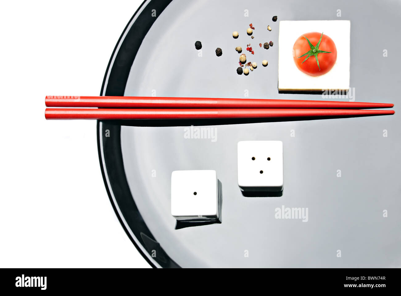Asian Food Composition. Chopsticks, cherry tomato, salt & pepper, and white tofu cheese on plate Stock Photo
