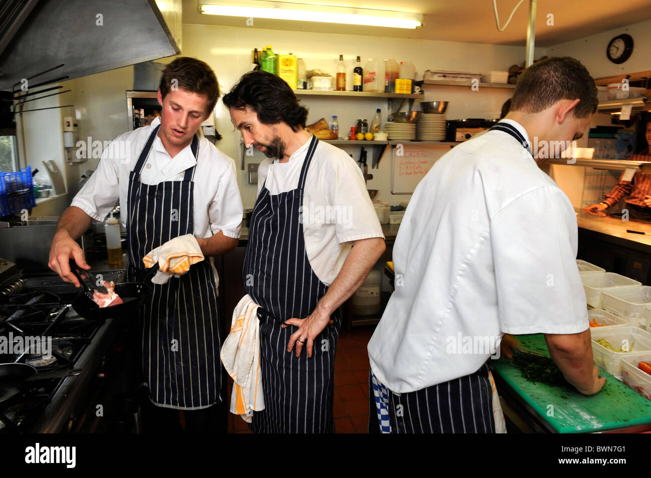 Head Chef Stephen Terry (centre) is shown the colouring of a piece of pork by Chef Ashley Woodland at The Hardwick restaurant Ab Stock Photo