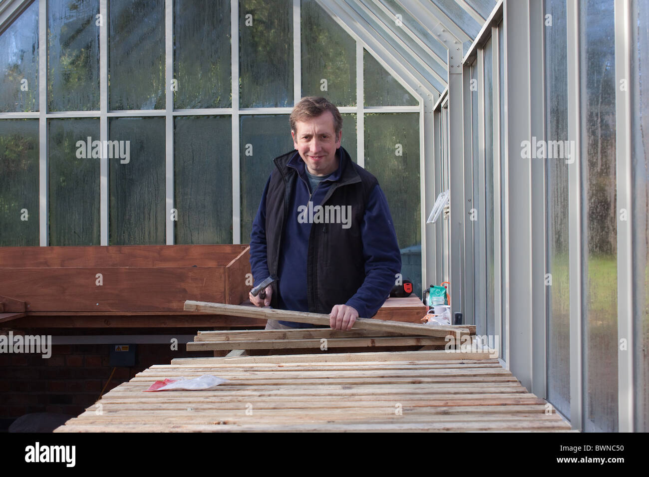 A man making greenhouse staging Stock Photo Alamy