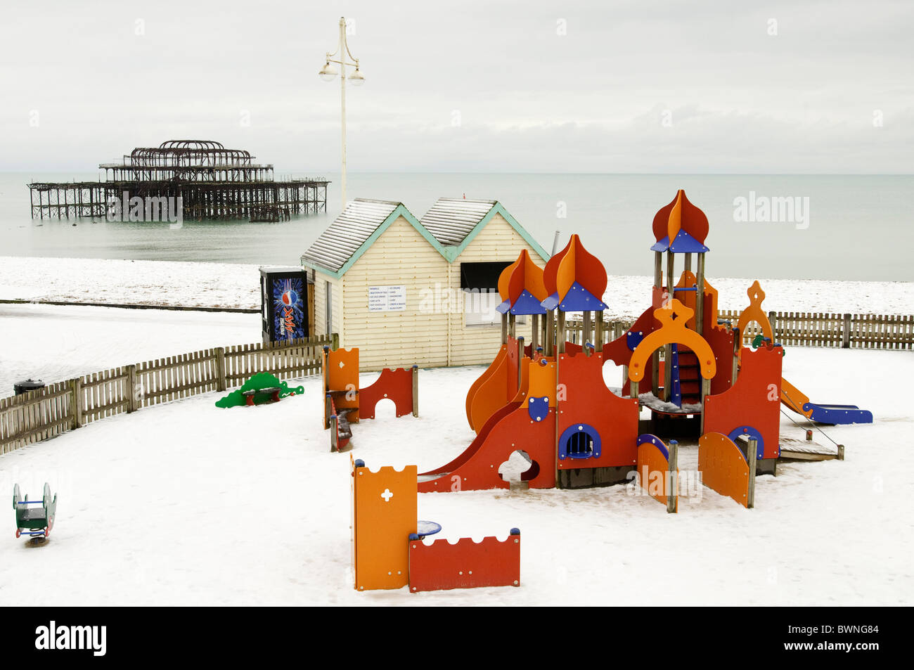 The shell of Brighton's west pier viewed across a deserted children's, snow covered playground Stock Photo