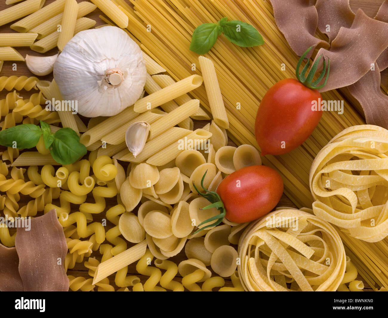 raw pasta with tomatoes garlic and basil Stock Photo