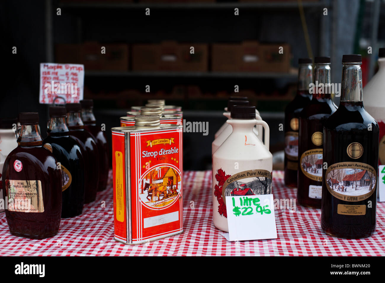 Various sizes and different containers of maple syrup at a farmer's