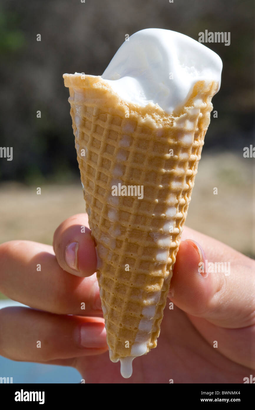 hand holding a melting ice cream in a cone with a drip Stock Photo