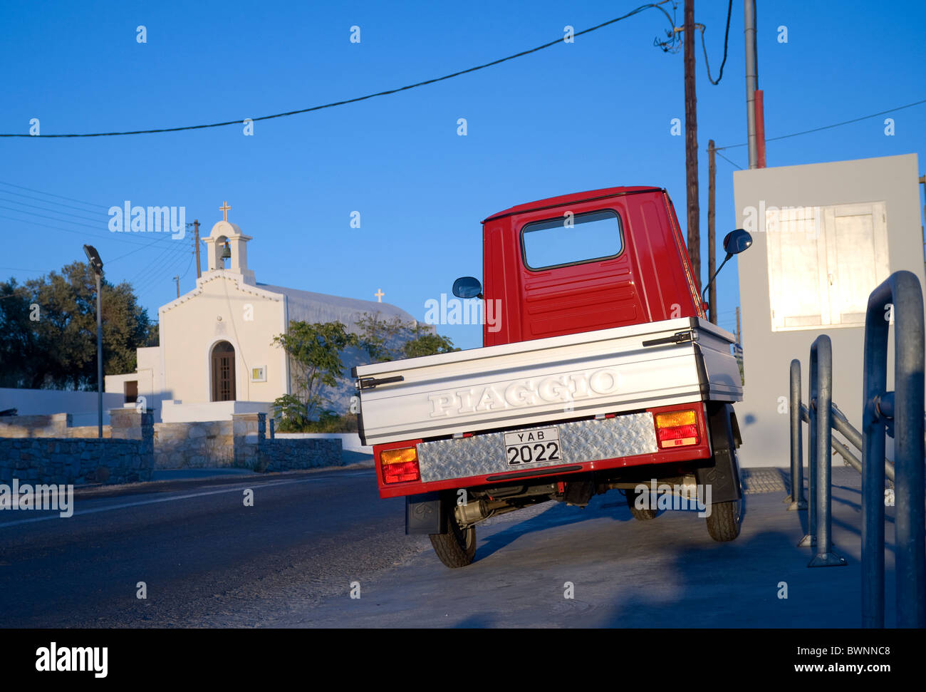 Back of a Piaggio Ape 50 three wheeler pick-up parked near a small church on the Greek Cyclade island of Syros. Stock Photo