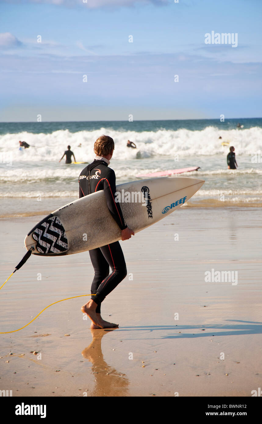 A surf enters the sea with his surfboard, Fistral Beach, Newquay, Cornwall, UK Stock Photo