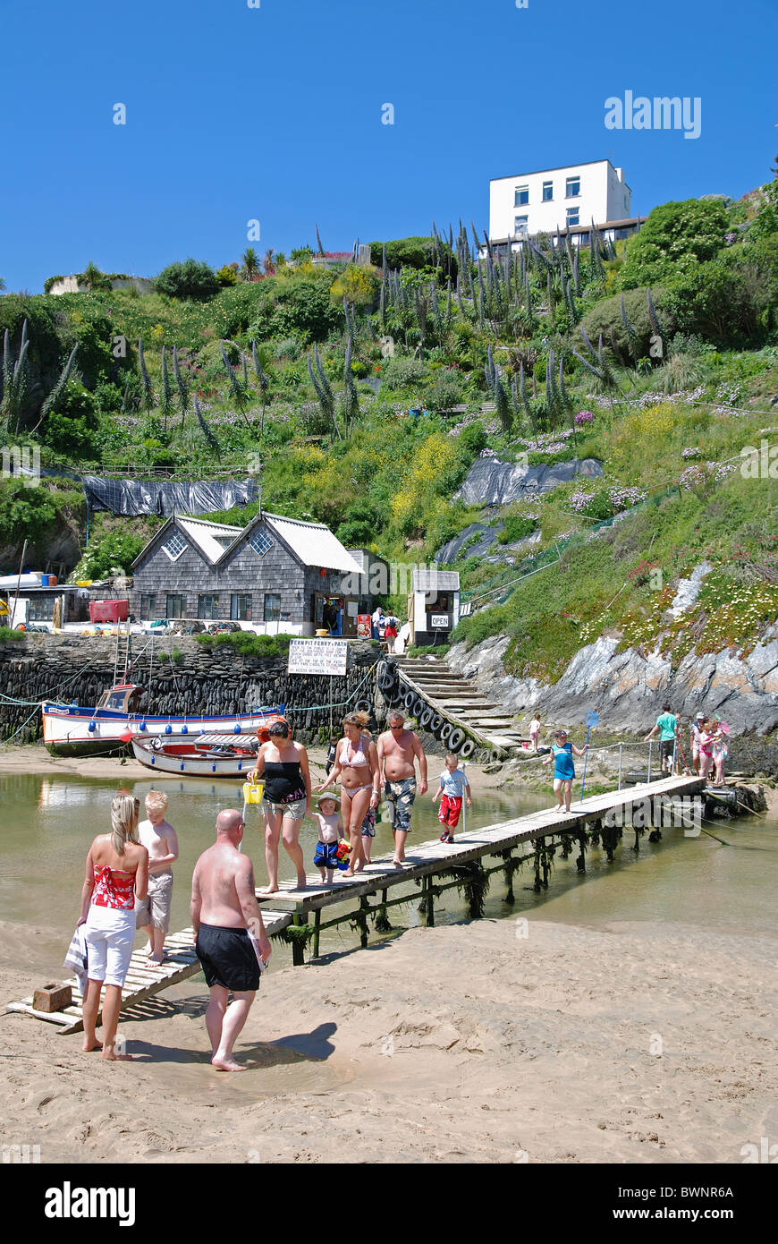 holiday makers crossing the little wooden bridge over the river gannel at crantock beach near newquay in cornwall, uk Stock Photo
