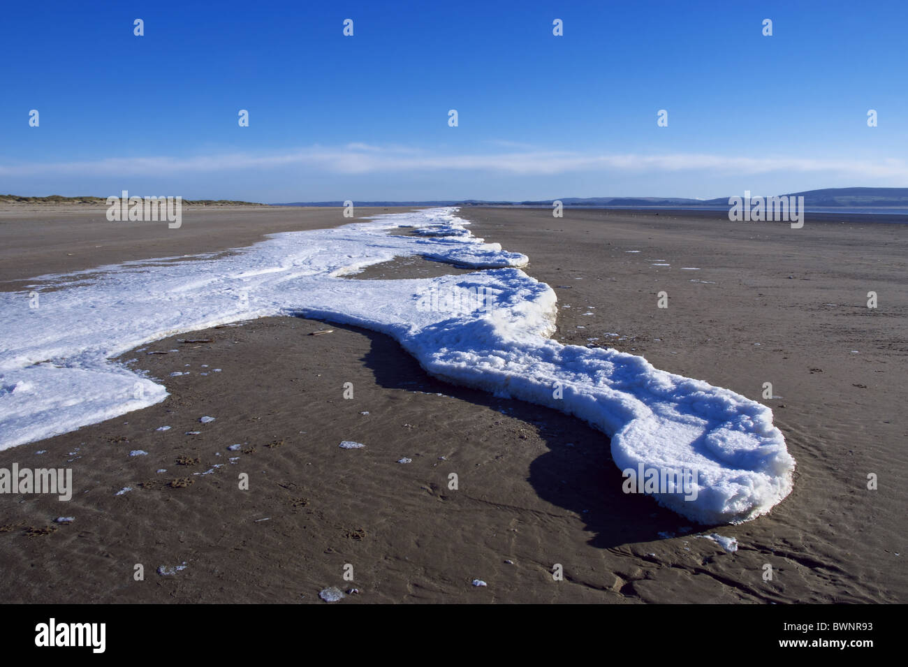 Sea ice along the tide line on the beach at Cefn Sidan in Wales. Stock Photo
