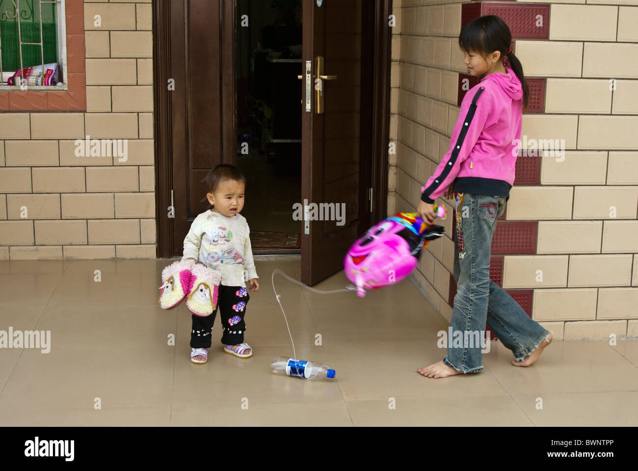 Dai girl playing with brother, Xishuangbanna, Yunnan, China Stock Photo