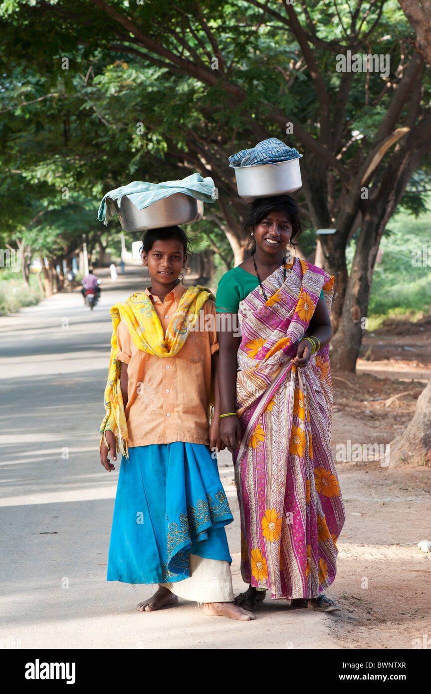Two lower caste indian teenage girls carrying pots of rice on their heads. Andhra Pradesh, India Stock Photo