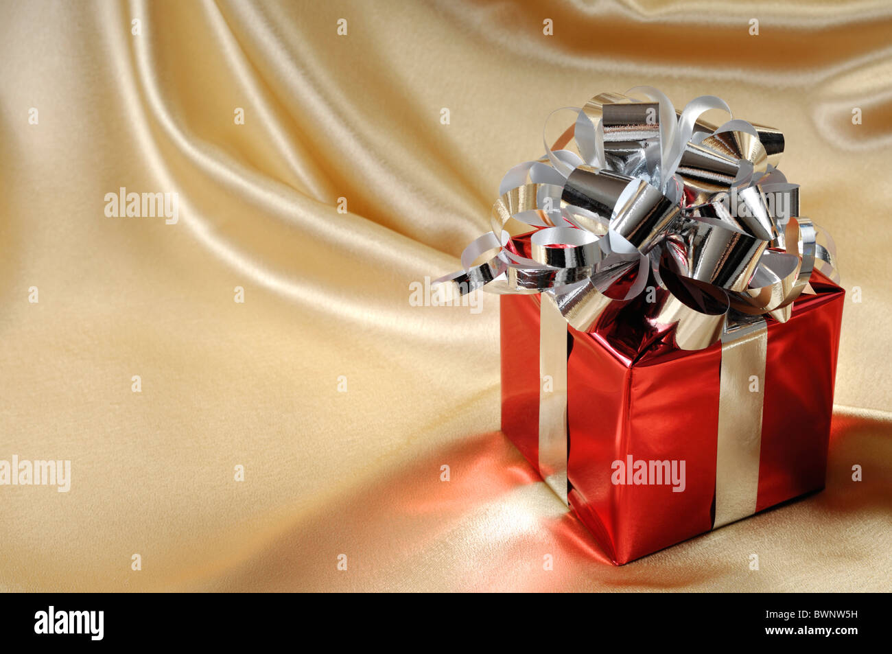 Red gift box with a silver bow on golden background Stock Photo - Alamy