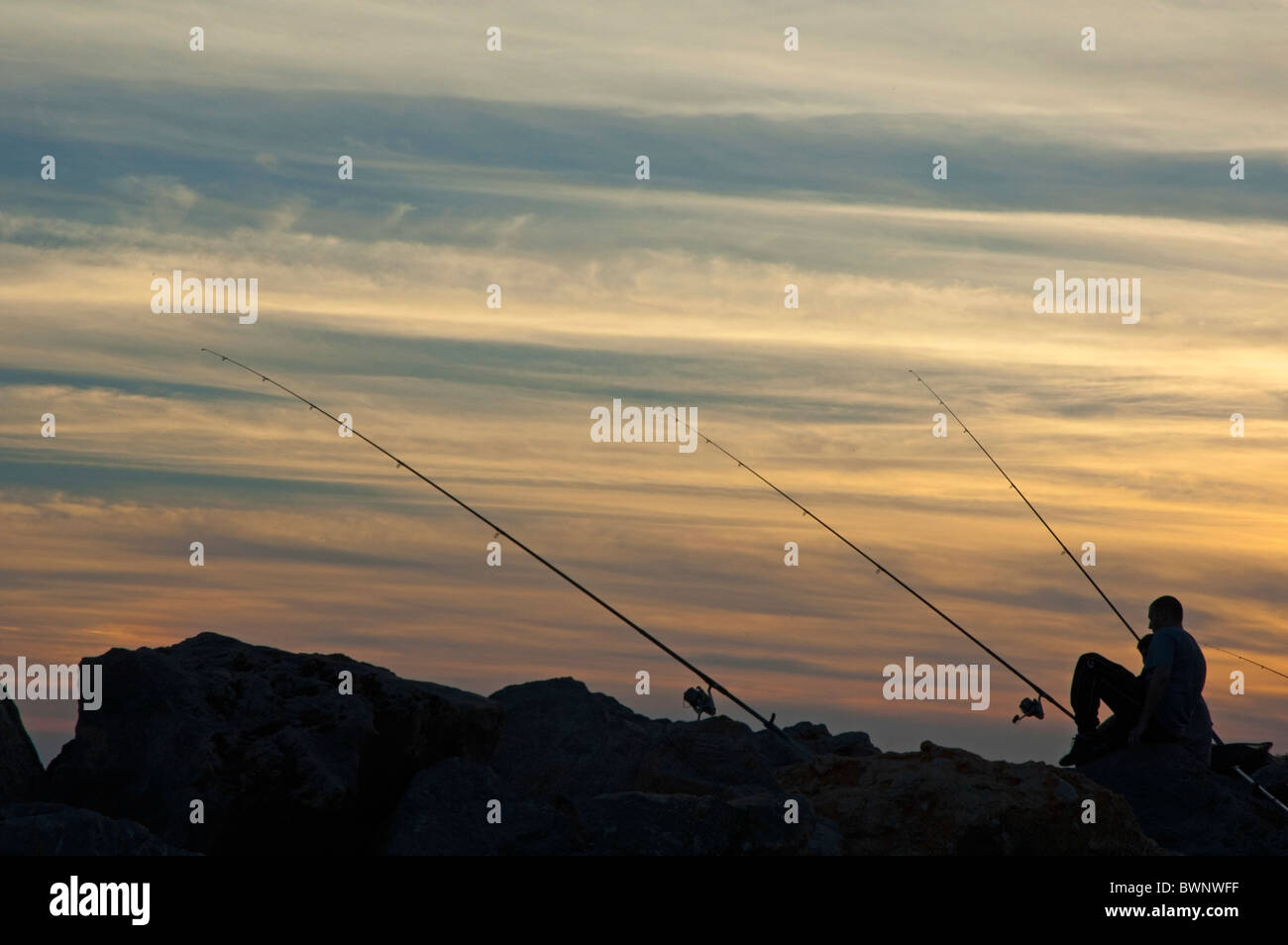 Silhouette of a fisherman at sunset. Stock Photo