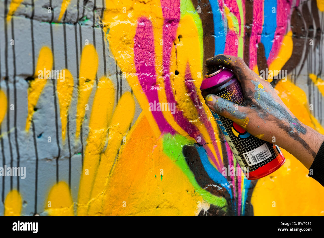 A Colombian artist sprays graffiti on the wall in La Candelaria, Bogota. Stock Photo