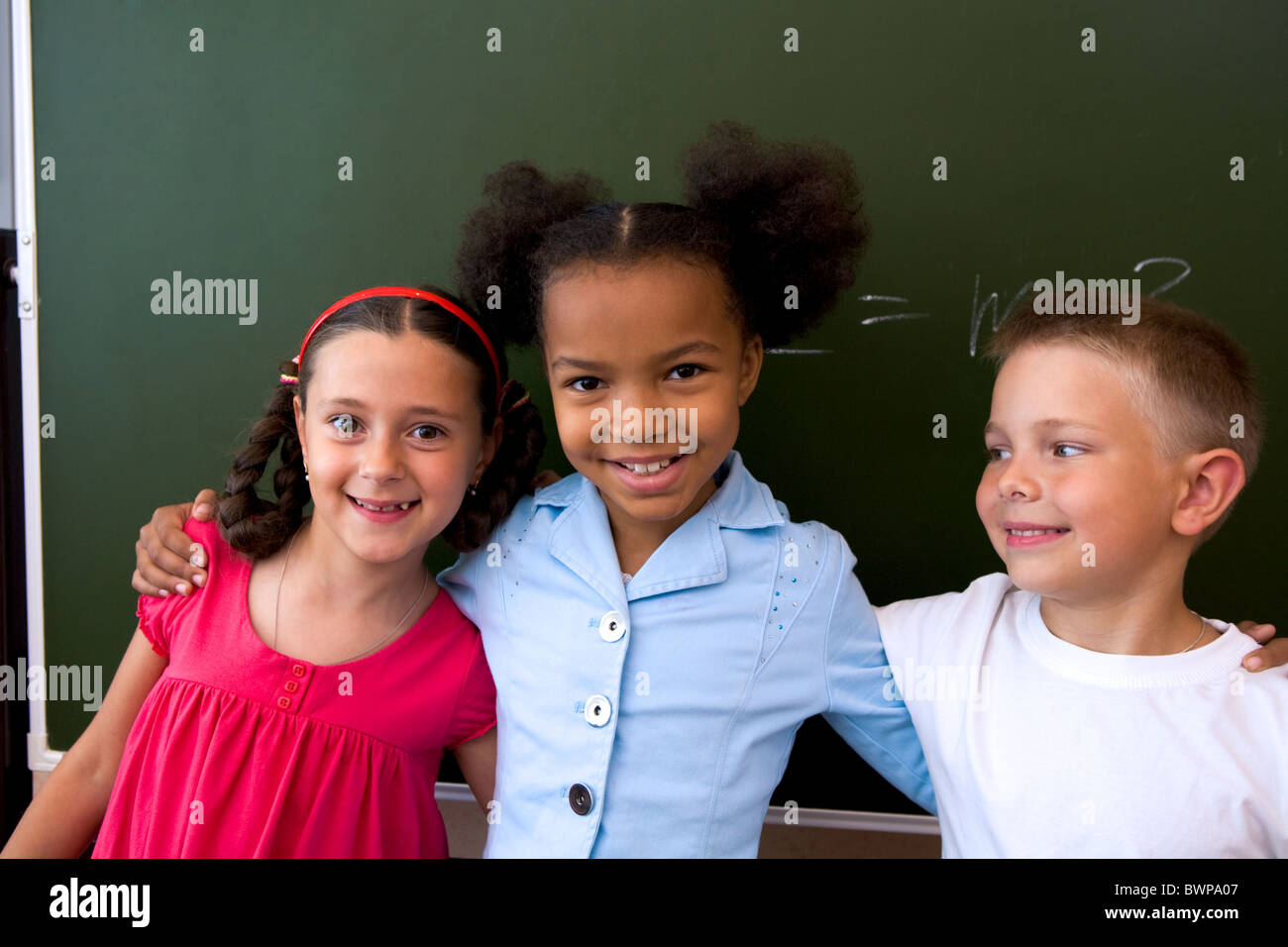 Image of clever classmates standing by blackboard and smiling at camera ...