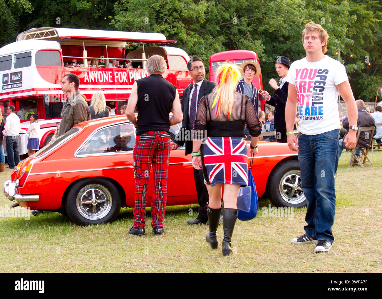 MGBGT with people making a range of fashion statements at Vintage at Goodwood Stock Photo