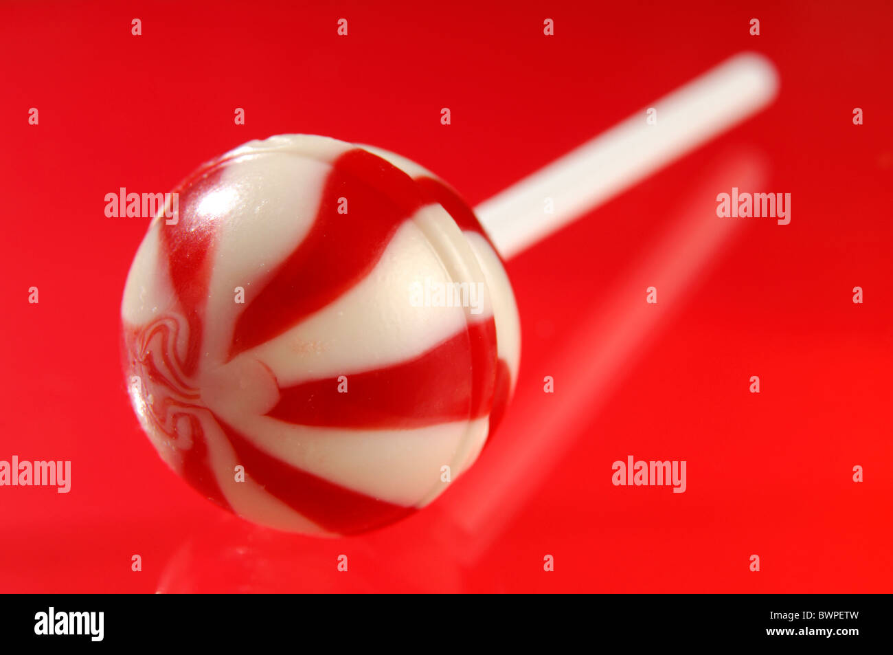Colorful red white stripy lollipop isolated on red background Stock Photo