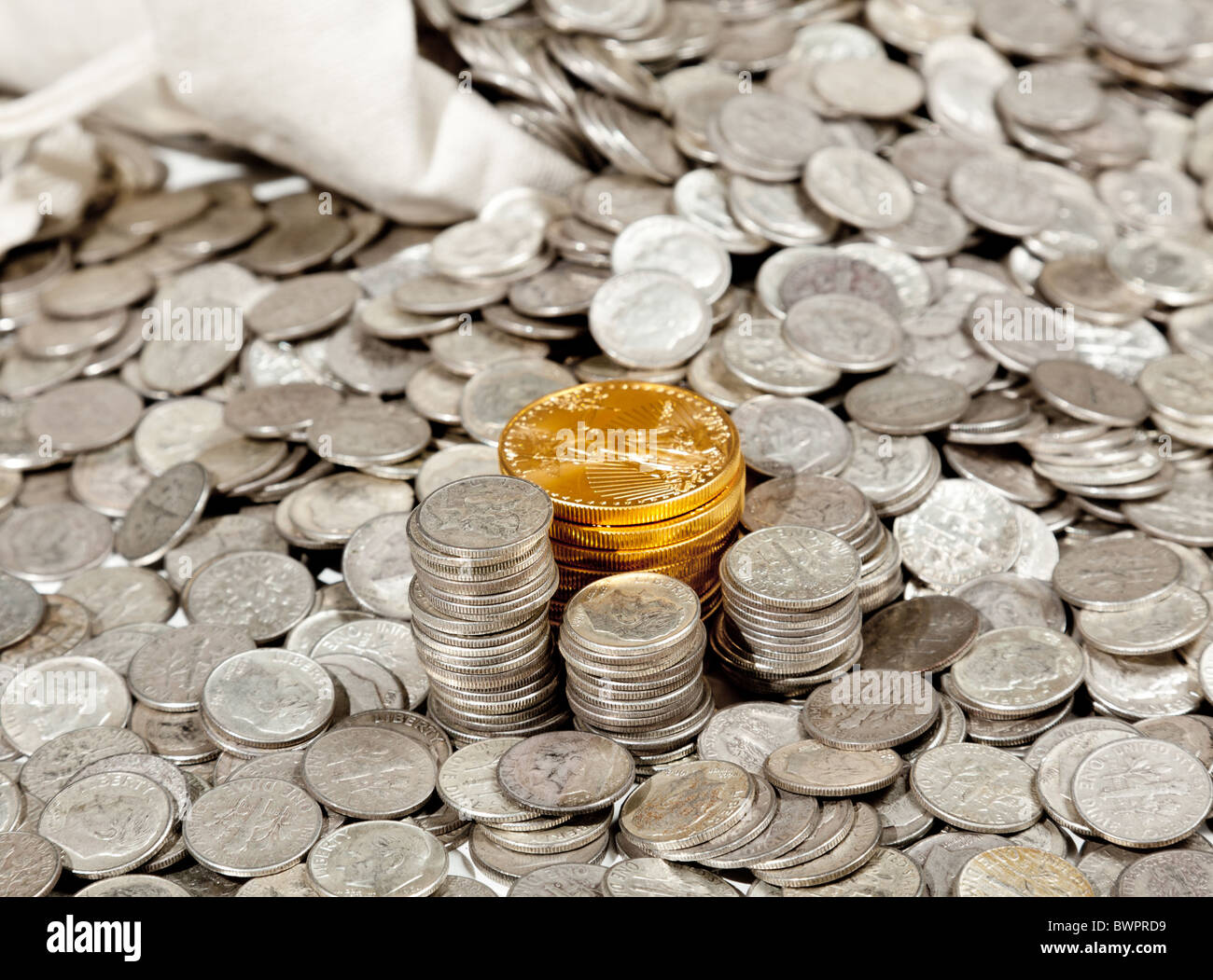 Linen bag of old pure silver coins used to invest in silver as a commodity with a selection of Golden Eagle gold coins Stock Photo
