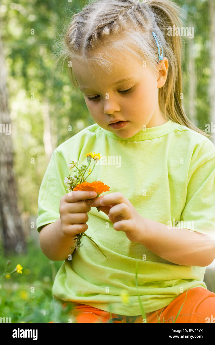 Portrait of innocent girl looking at flowers in her hands Stock Photo