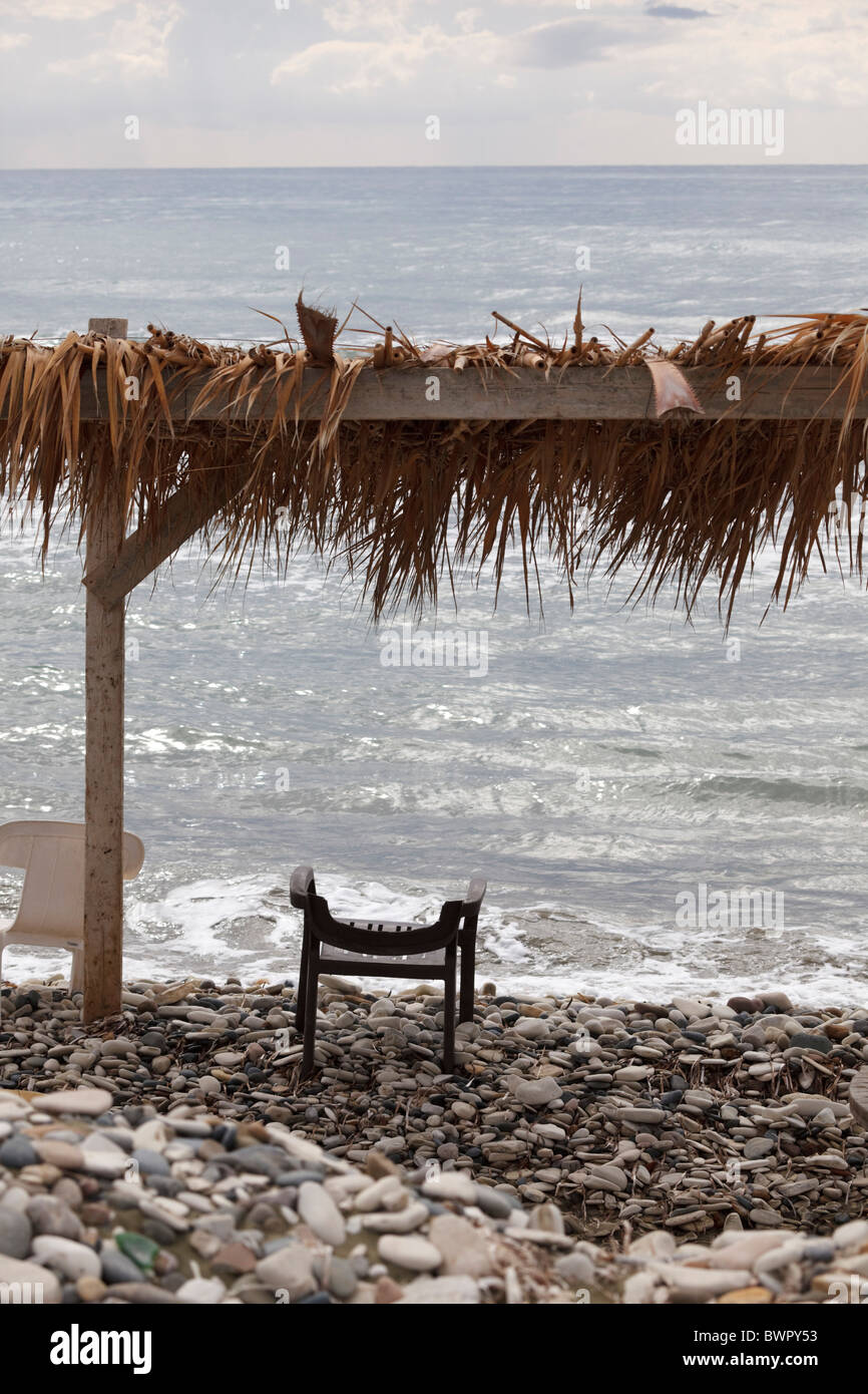 Plastic chair under a sunshade on the beach at Perivolia, Larnaca, Cyprus Stock Photo