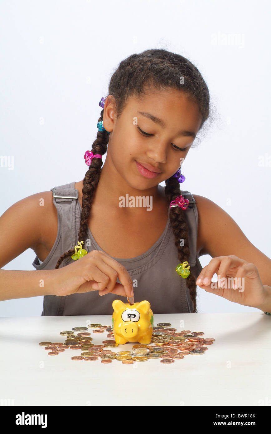 A girl with her savings and a piggy bank Stock Photo