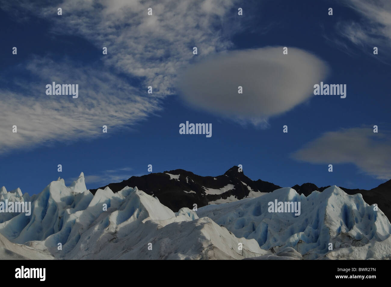 Cloud On Ridges Blue sky and lens-shape cumulus cloud above ce gullies and ridges on ...