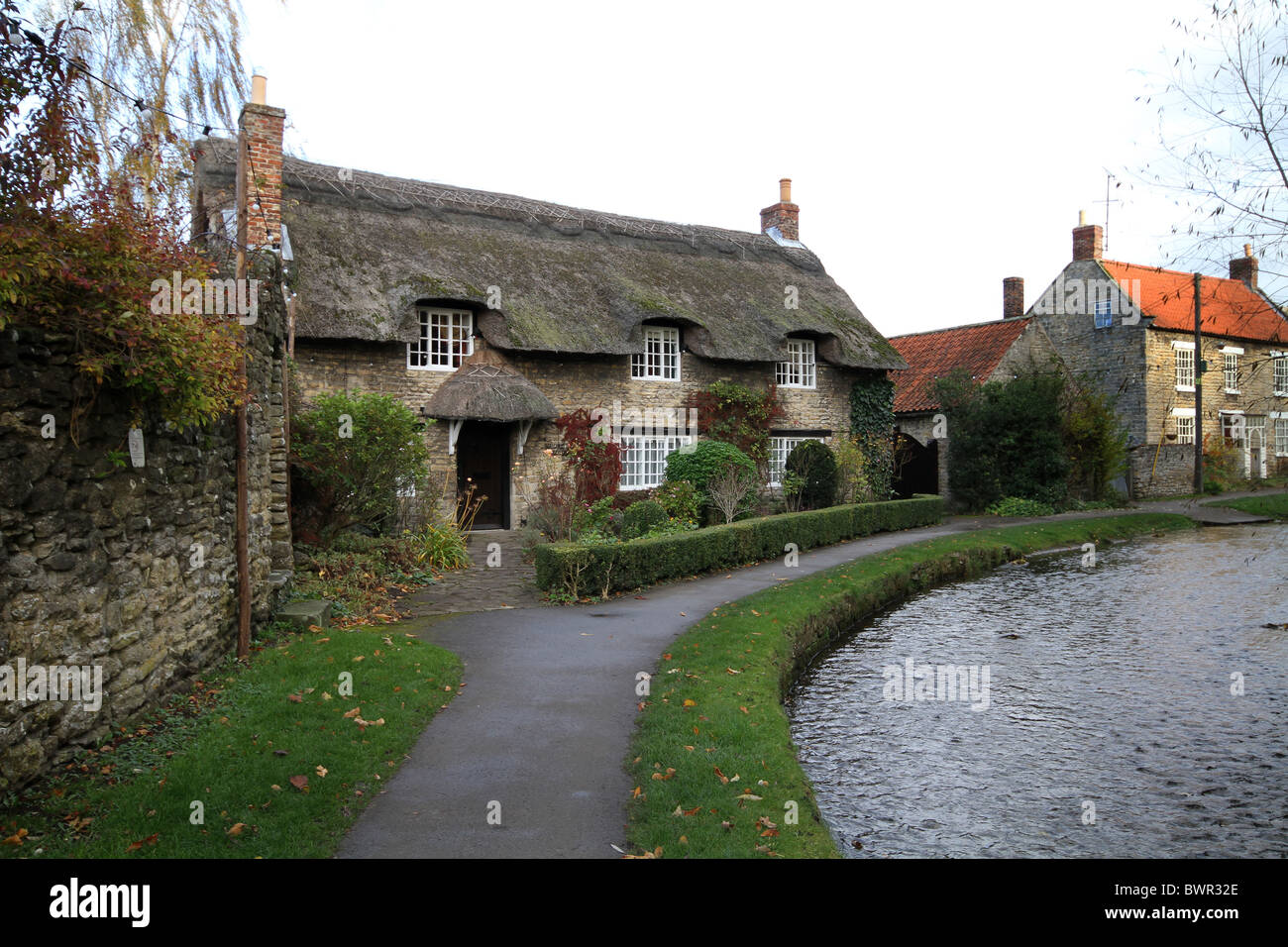 Thatched cottage by the stream in Thornton Le Dale in North Yorkshire. Stock Photo