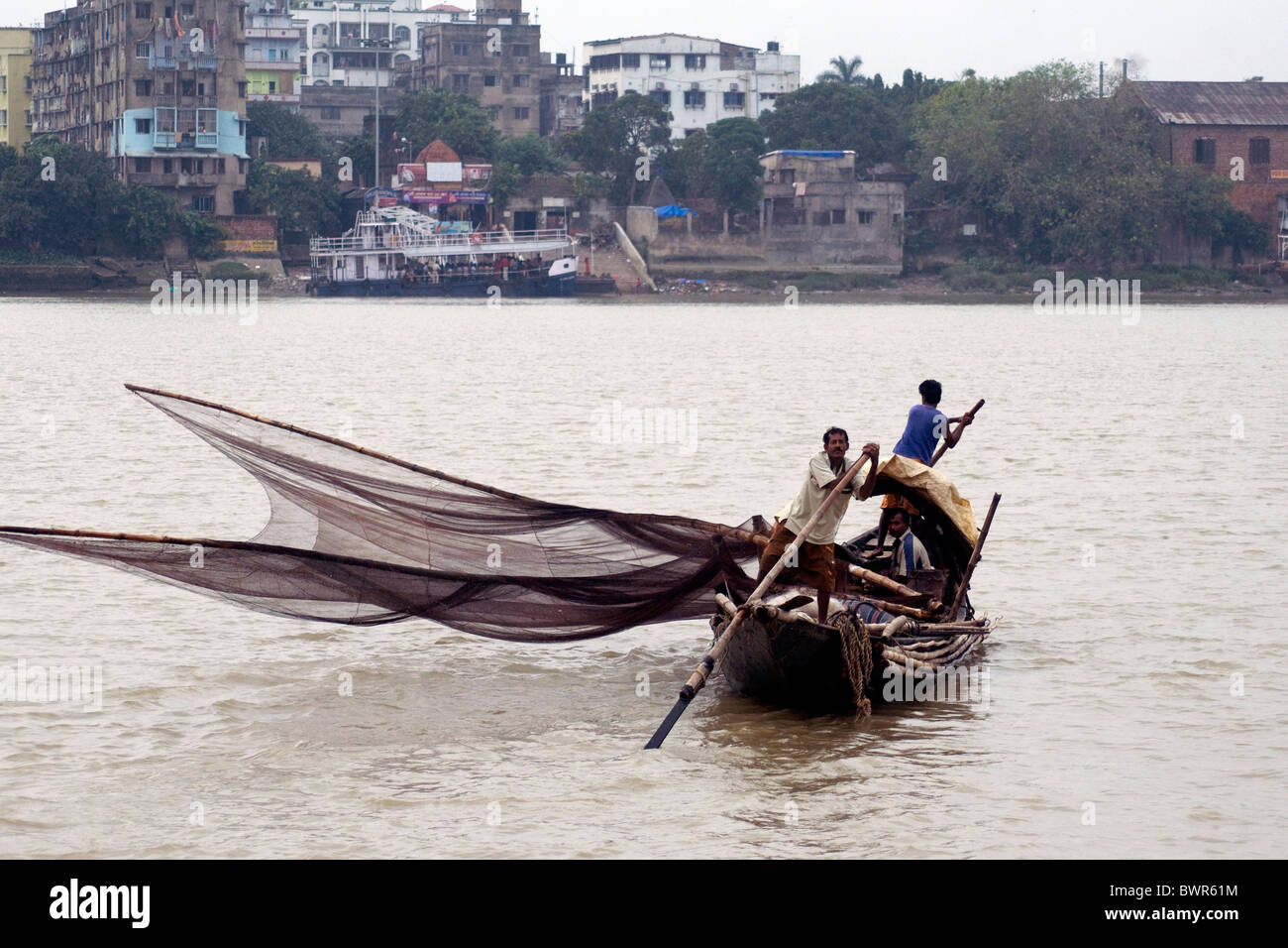 A small fishing boat casts its net into the Hooghly river near Kolkata, India Stock Photo